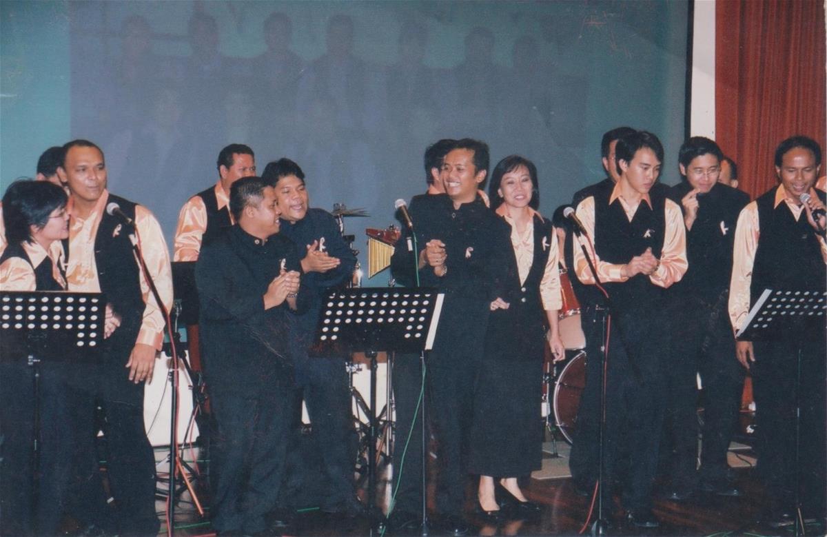 The SCDF Combo band singing a joint medley with the Police band. The SCDF Combo band members are in long orange sleeves...